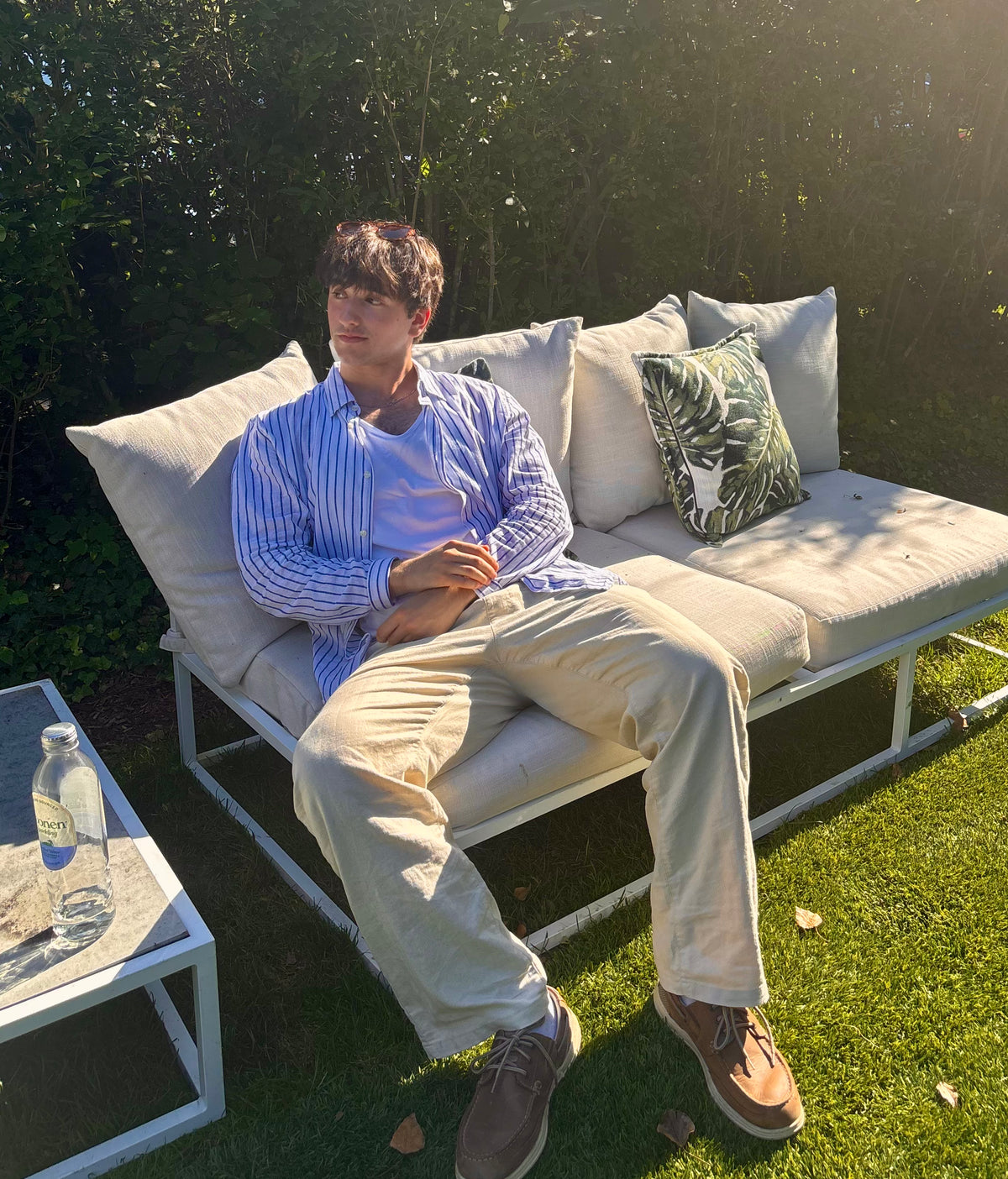 Evan Amadio, Founder and Formulator of Eukomos, sitting on a white outdoor daybed on a sunny lawn.