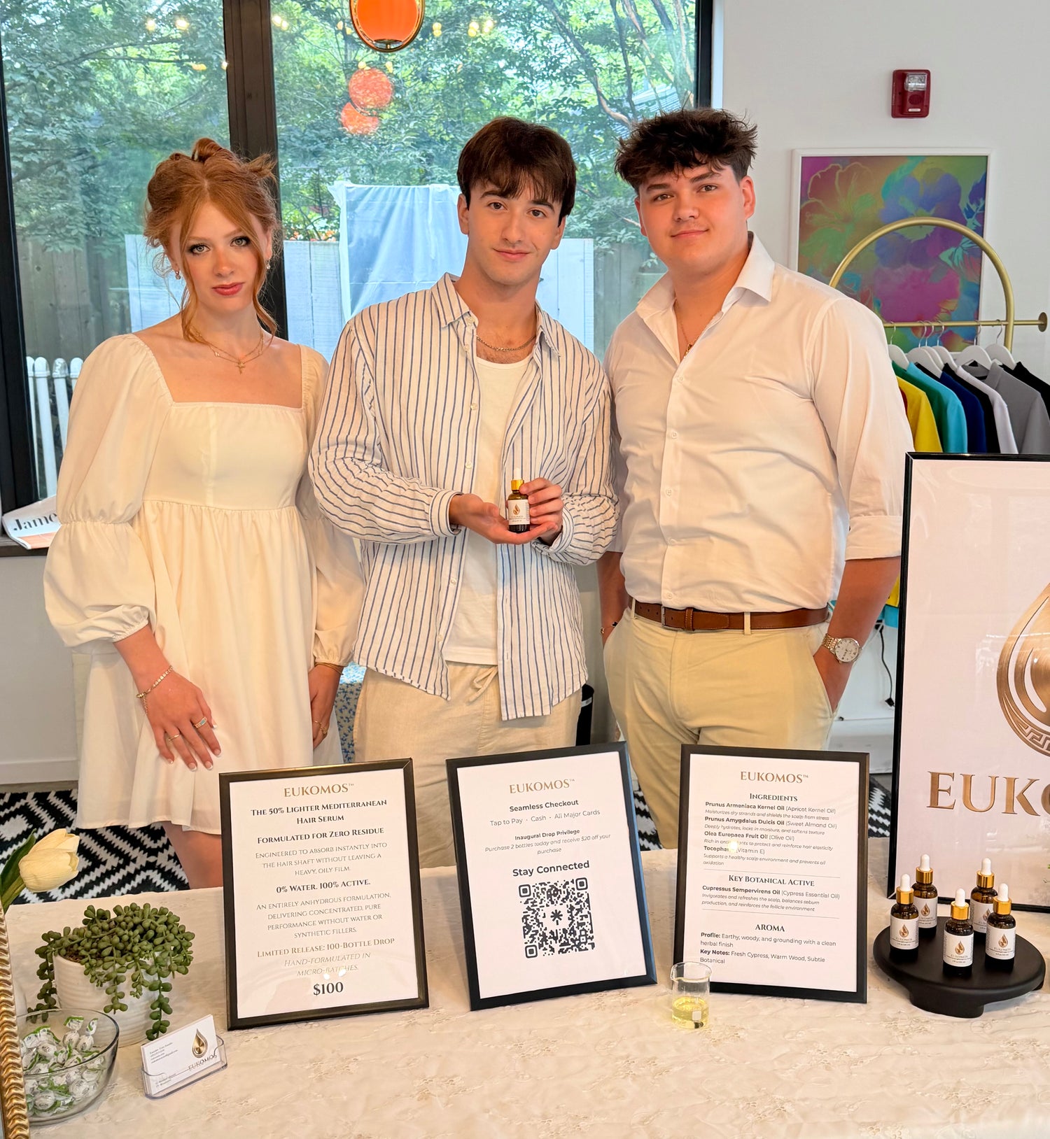 Eukomos founder Evan Amadio and his PR team standing behind a pop-up vendor table displaying Eukomos luxury botanical serum and branded signage.